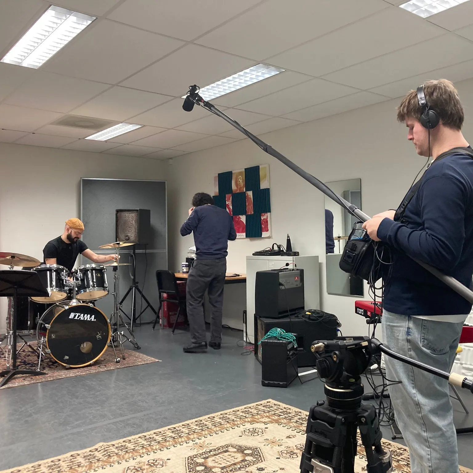 geluidsman en man achter drumstel in repetitiehok