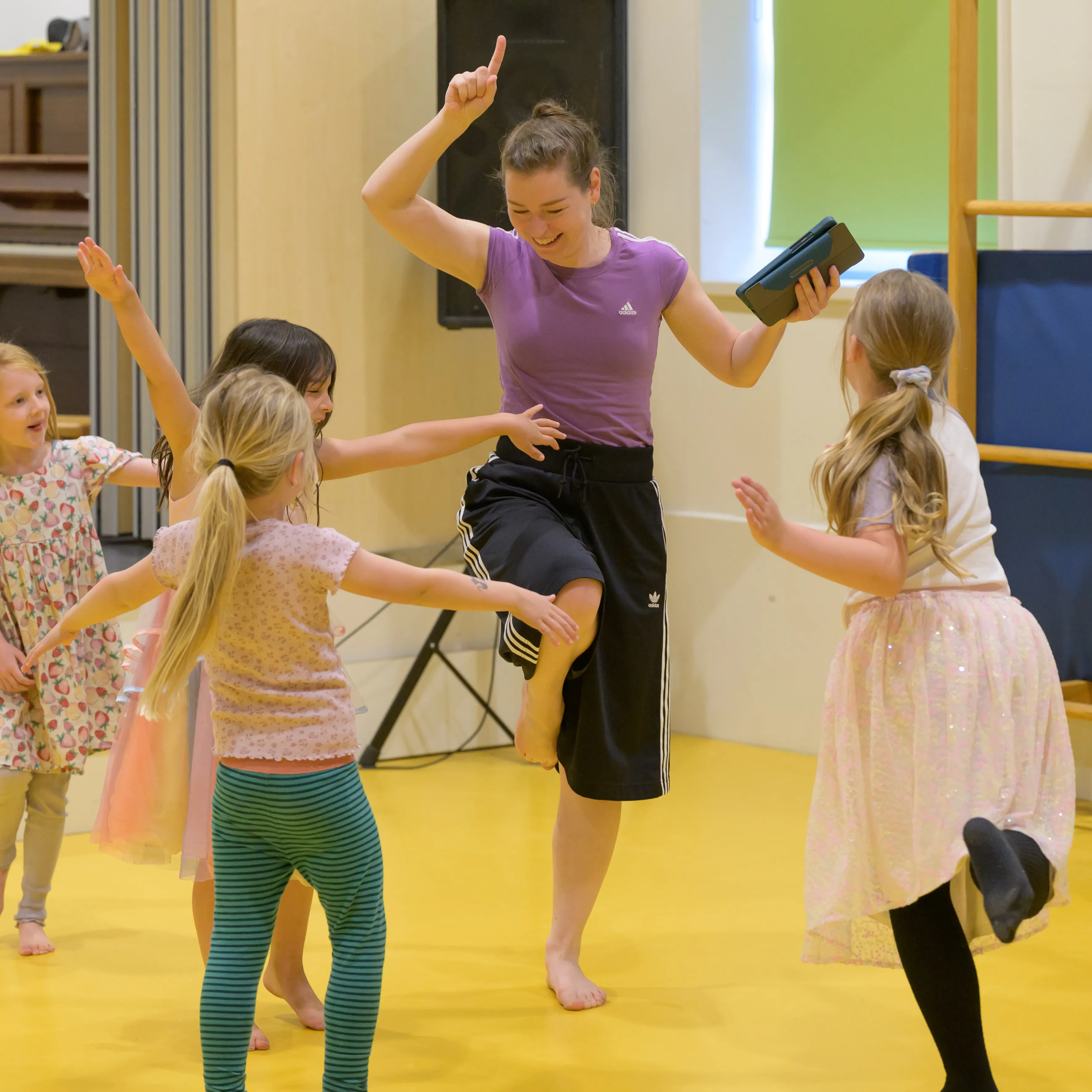 Juf aan het dansen met kinderen in gymzaal