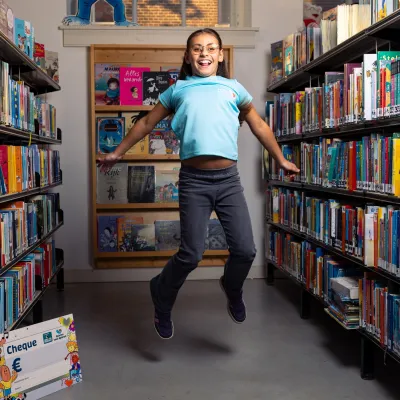 Meisje springt tussen boekenkasten