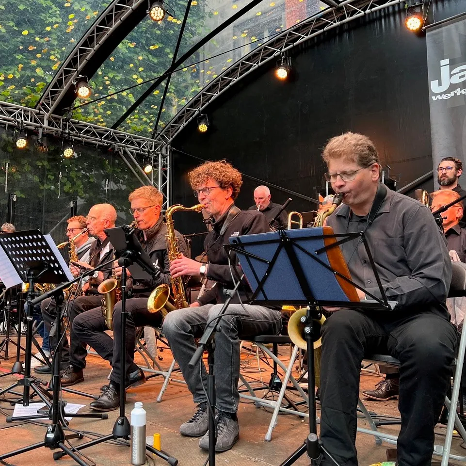 Big band op podium zittend op stoel met instrumenten