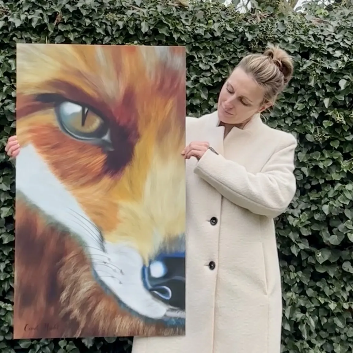 Vrouw met witte jas houdt groot portret vast van vos