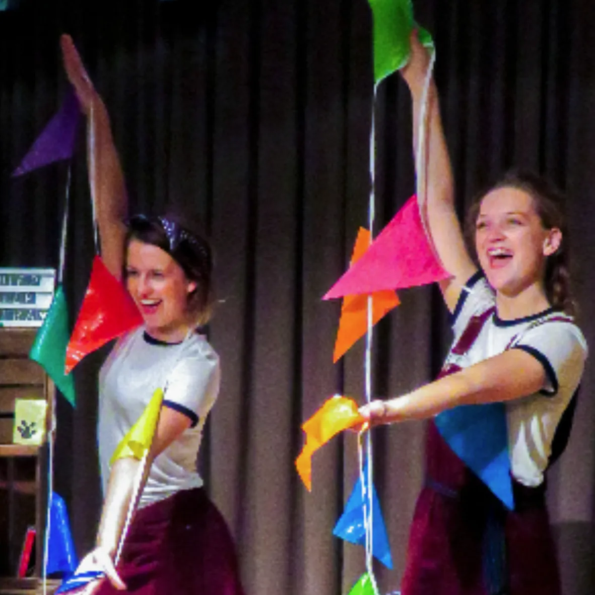 Foto van eerdere show van Letter Belangrijk, waar beide actrices op in beeld zijn met een gekleurde vlaggenslinger