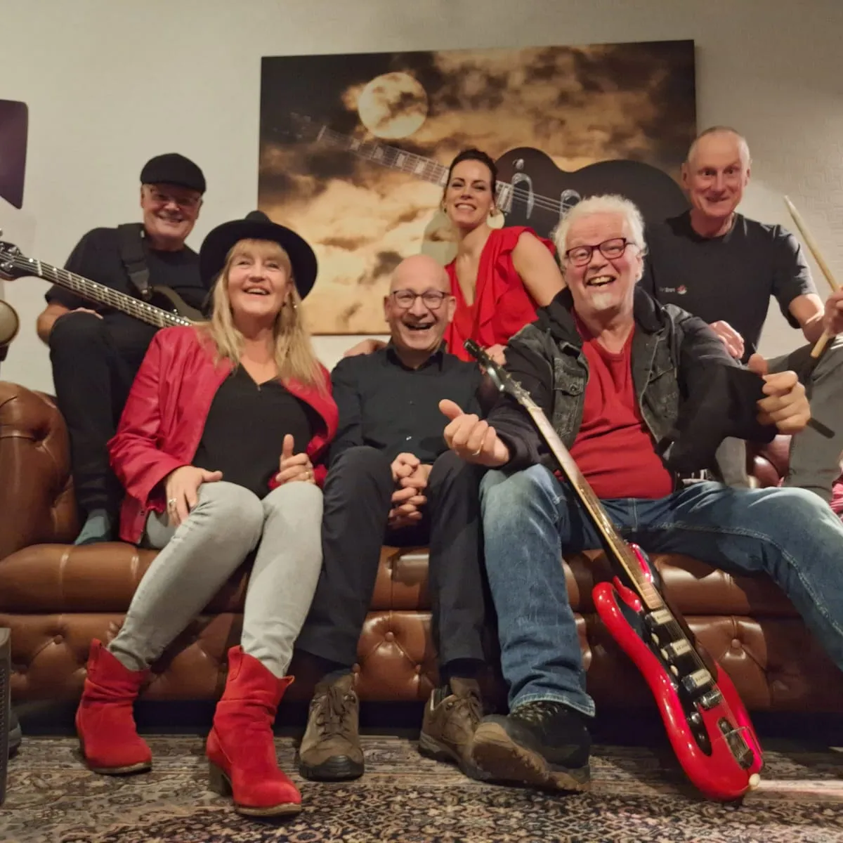 Bandleden met instrumenten zittend op bank