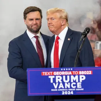Donald Trump en JD Vance die elkaar de hand schudden.