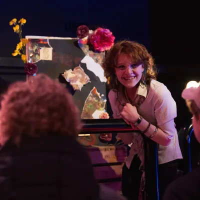 lachende jonge vrouw die haar kunst laat zien aan een publiek, kunstwerk met bloemen
