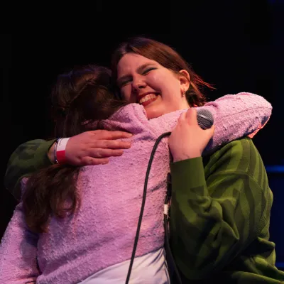 twee jonge vrouwen knuffelen, roze vest, groene trui