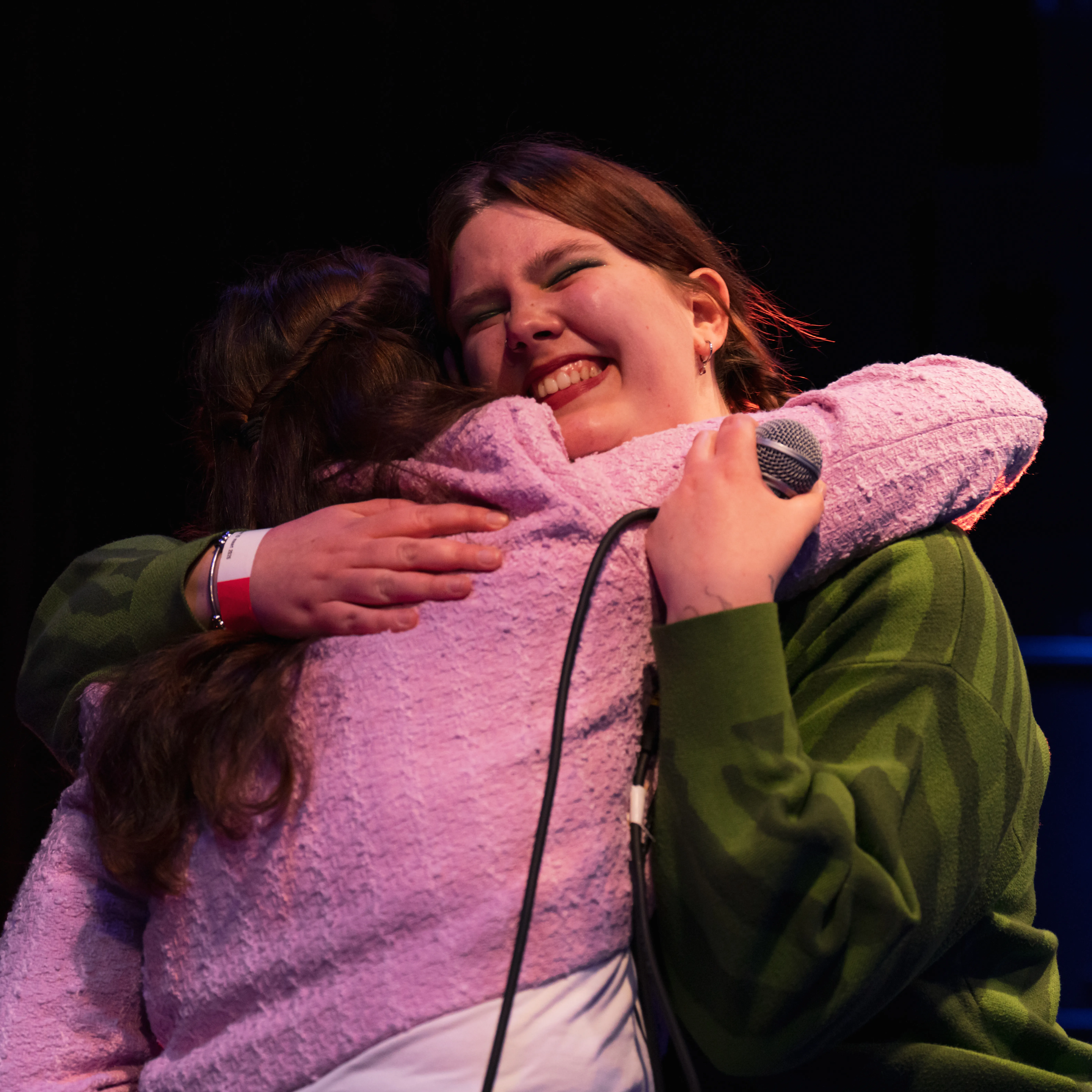 twee jonge vrouwen knuffelen, roze vest, groene trui