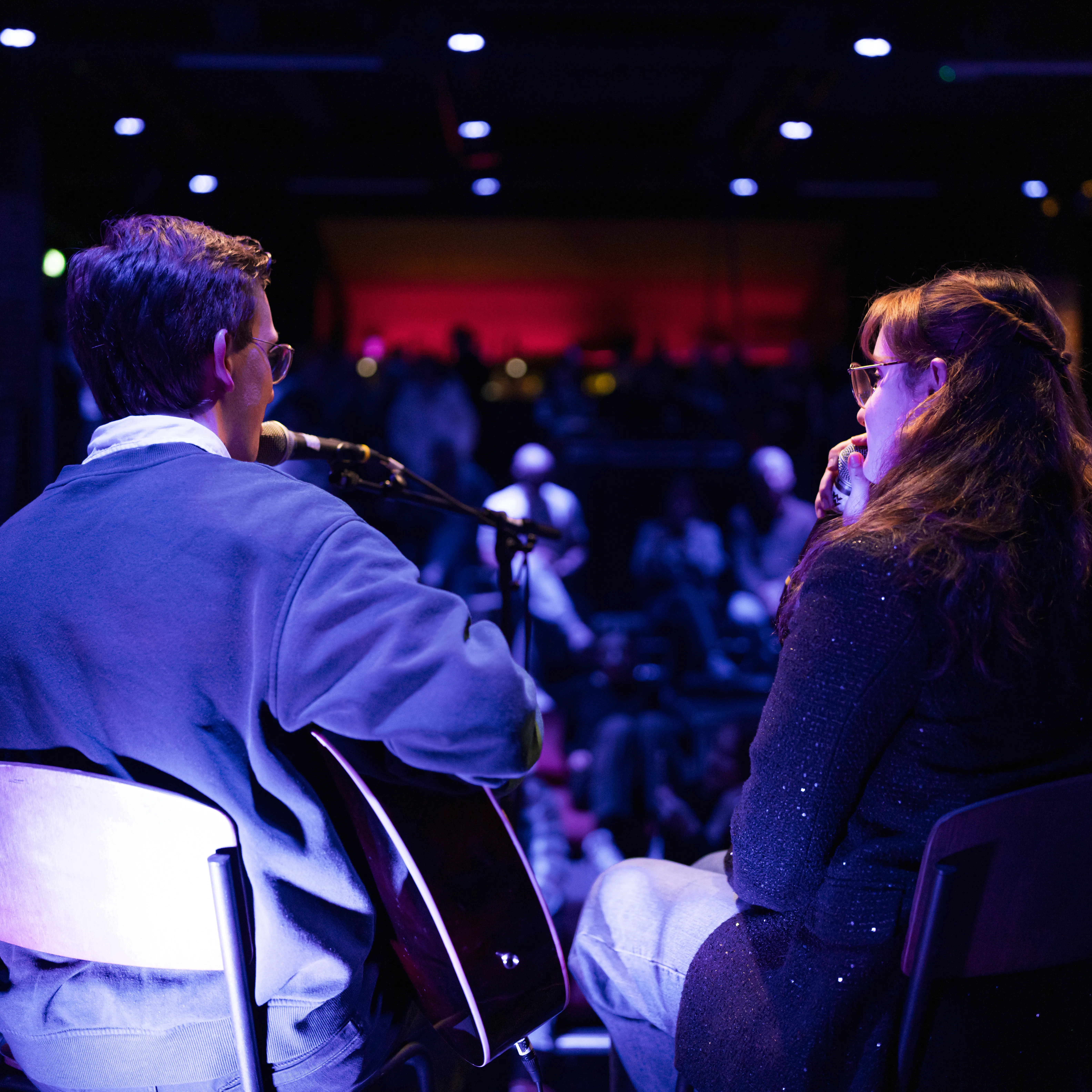 twee jonge mensen met publiek, spelen gitaar en zingen 