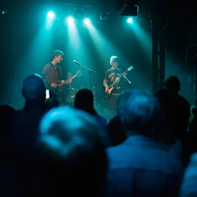 Volle zaal rock band groen blauw licht podium twee personen gitaren en zang