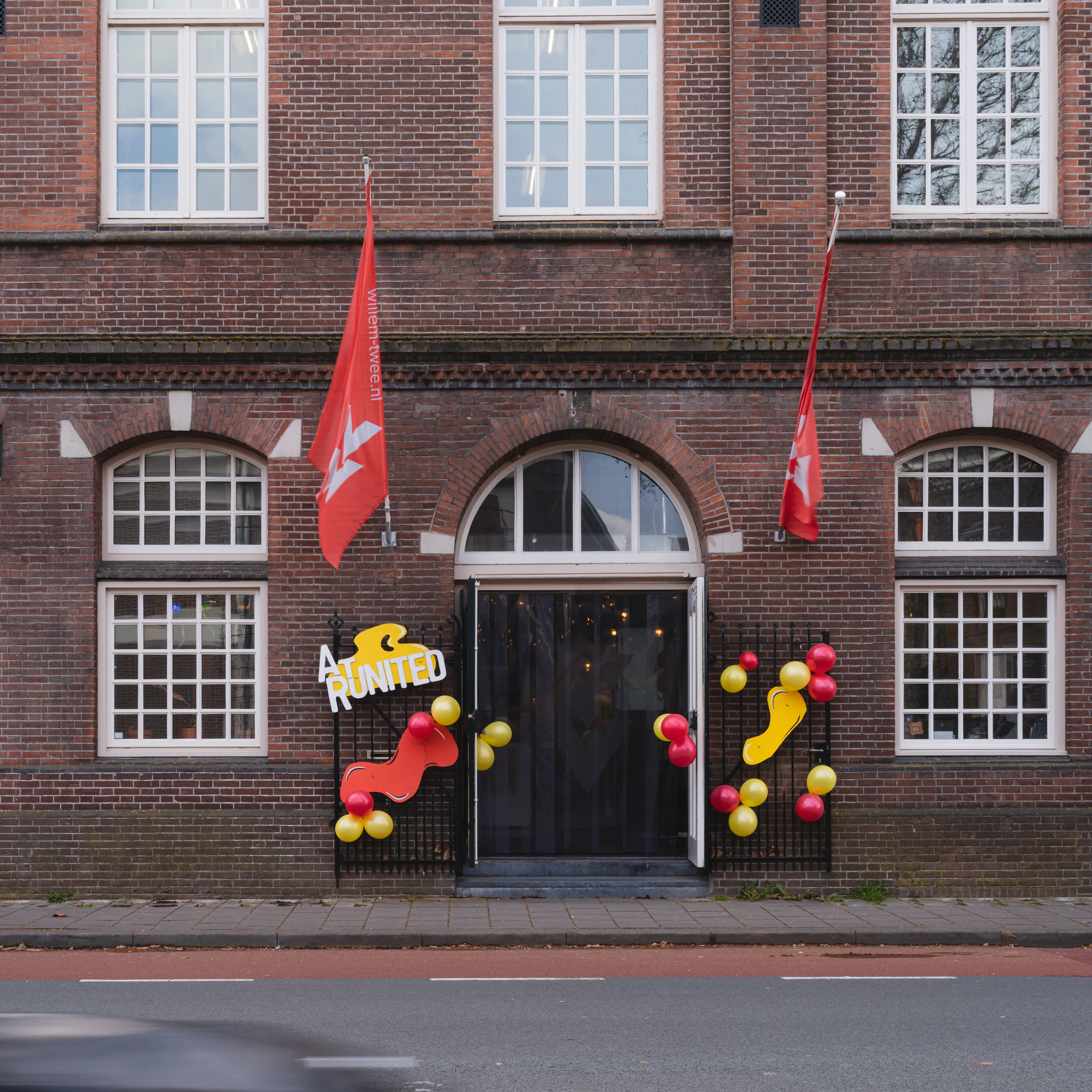 Voorkant van een pand met ballonnen en vlaggen 