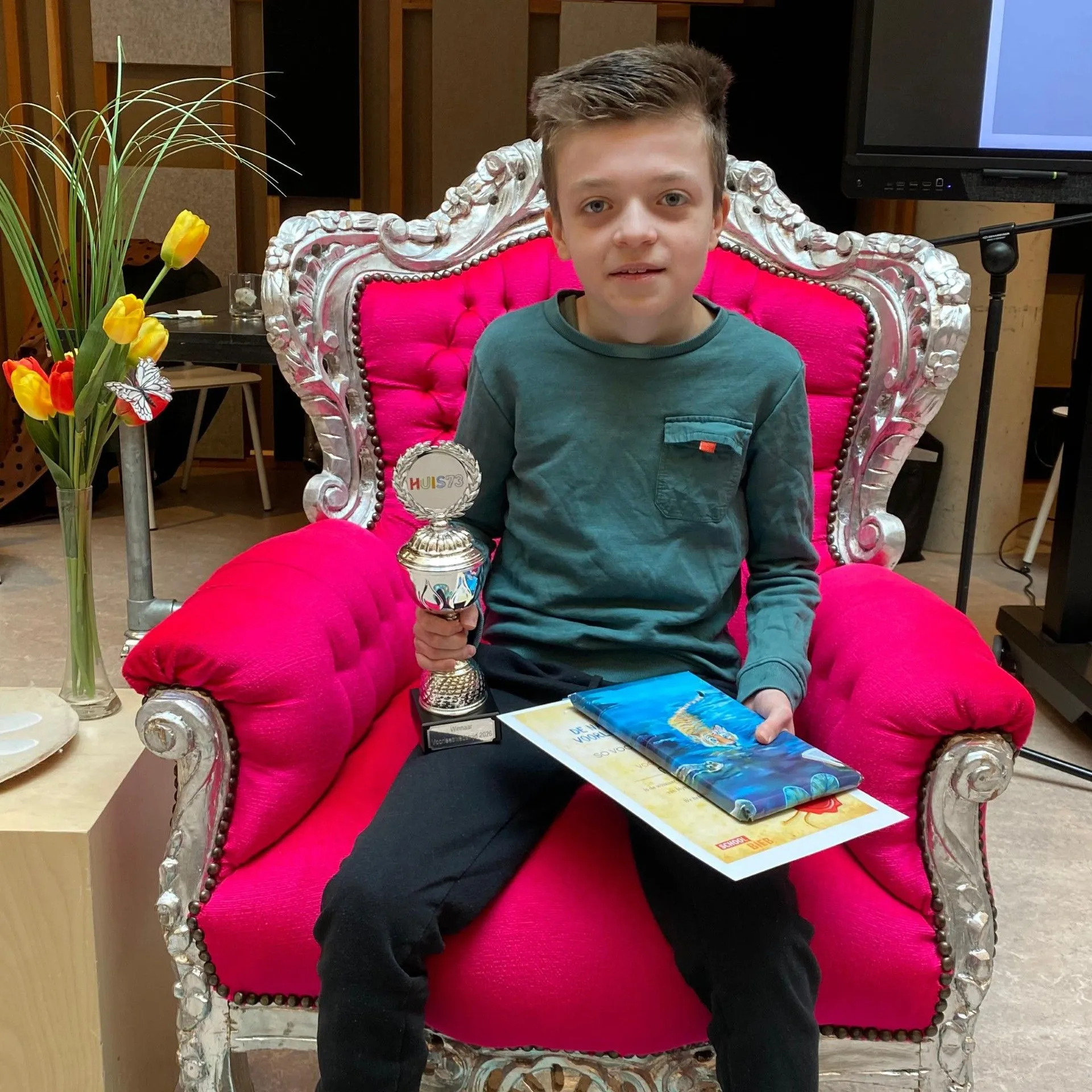 jongen met boek en prijs en rode voorleesstoel