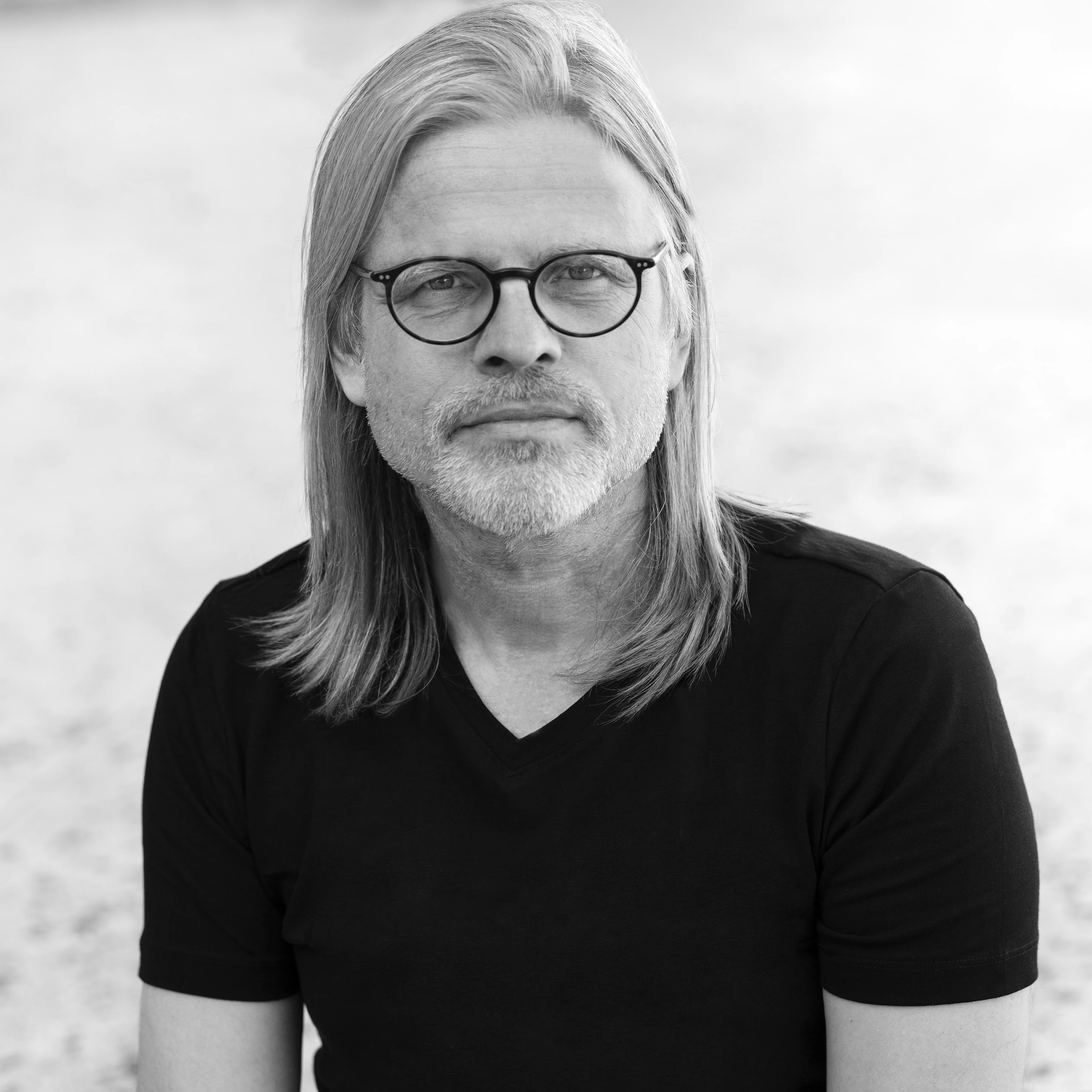 De schrijver is te zien: lang sluik haar, snor en bril. 