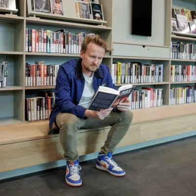 man lezend voor boekenkast