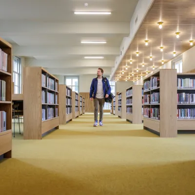 man wandelend tussen boekenkasten