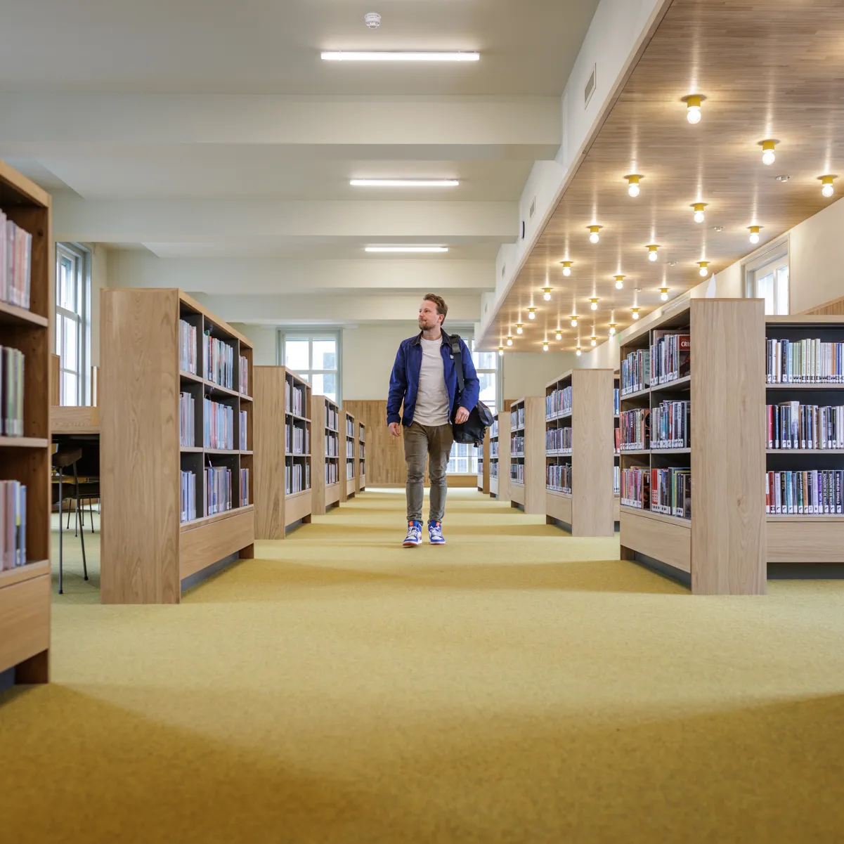 man wandelend tussen boekenkasten