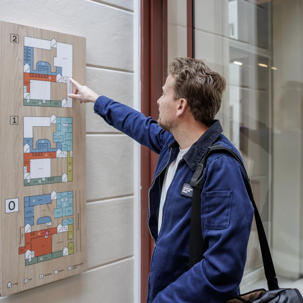jonge man met blauw jasje bij wegwijzerbord