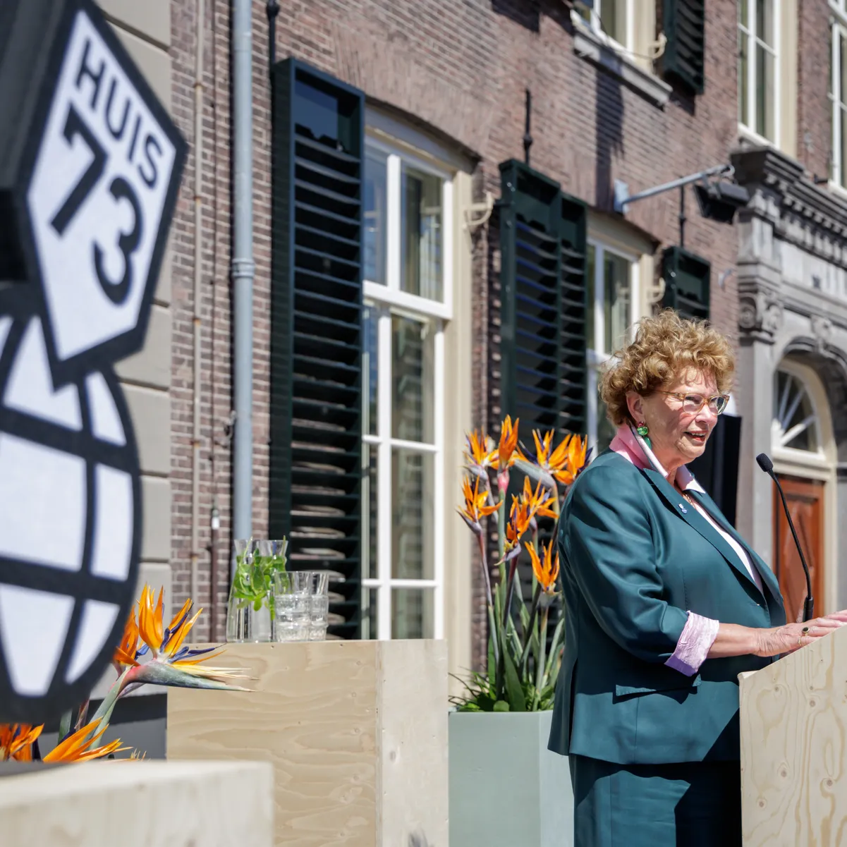 directeur in groen mantelpak houdt toespraak buiten