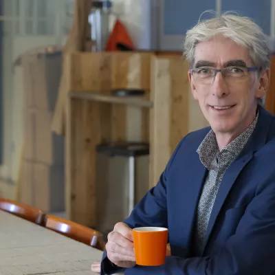 man met grijs haar en een bril met een kopje koffie
