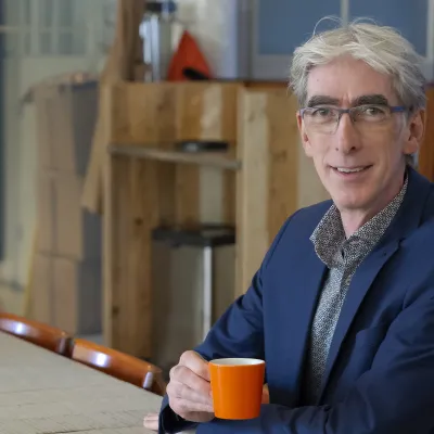 man met grijs haar en een bril met een kopje koffie