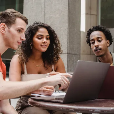 Drie jongeren die samen naar een laptopscherm kijken