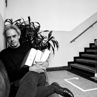 Zwart-wit foto van Eric Alink op stoel met achter hem een plant en een trap