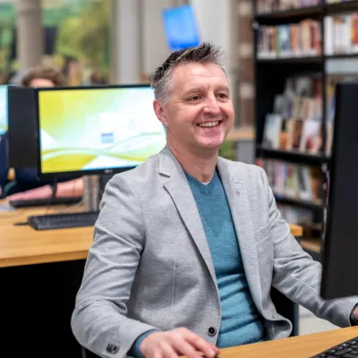 lachende man achter computer 
