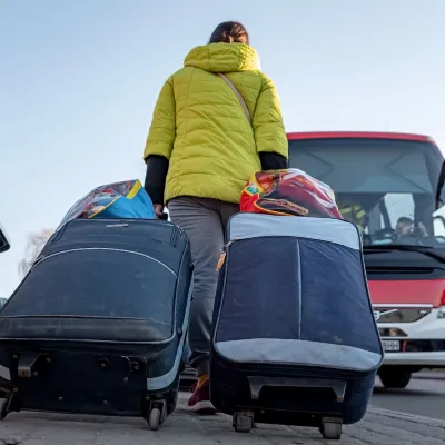 Een vrouw met koffers loopt naar een bus