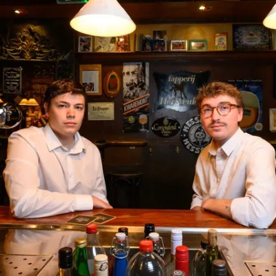 Twee jonge mannen in witte overhemden in een bruine kroeg