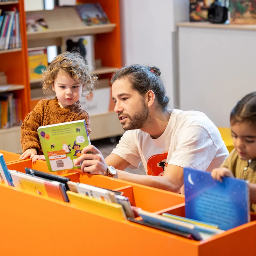 man en kinderen bij lage boekenkast