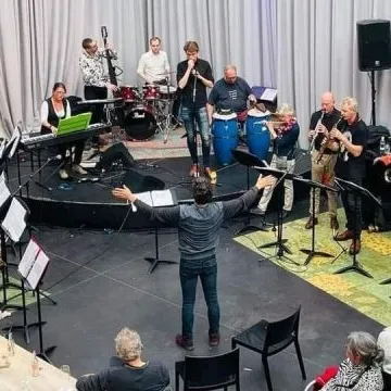 Grote band met instrumenten op het podium van Huis73